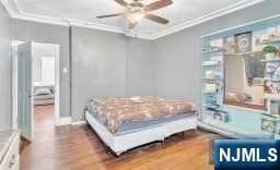 bedroom featuring hardwood / wood-style floors, ceiling fan, and ornamental molding