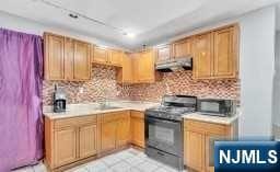 kitchen with decorative backsplash, black electric range oven, and sink