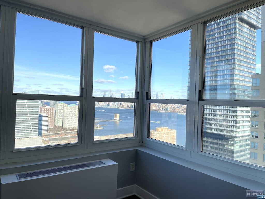 unfurnished sunroom with radiator, a water view, and a wealth of natural light