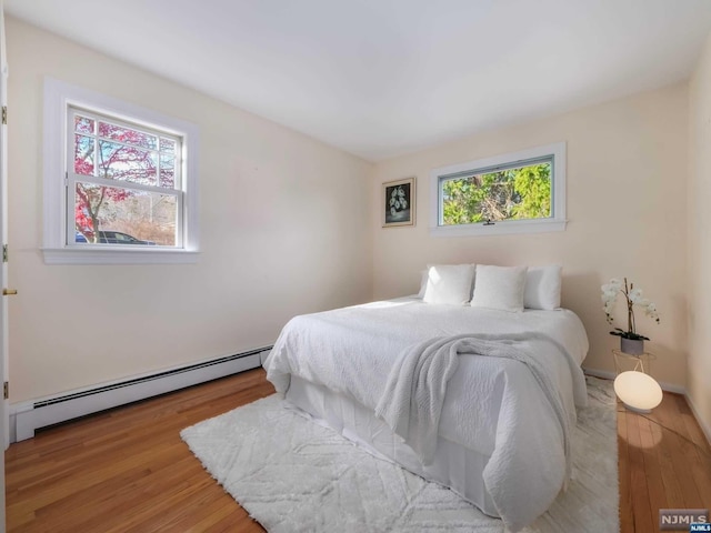 bedroom featuring light wood-type flooring and baseboard heating