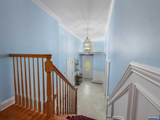 staircase with wood-type flooring, ornamental molding, and a notable chandelier