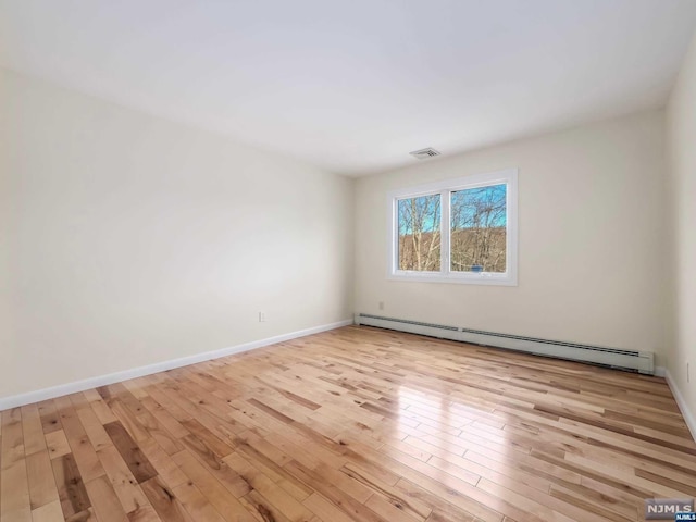 unfurnished room with light hardwood / wood-style flooring and a baseboard heating unit