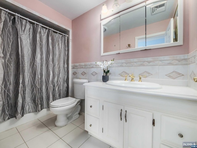 bathroom with vanity, a shower with curtain, tile patterned flooring, toilet, and tile walls