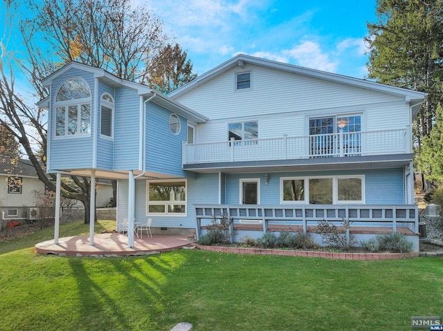 rear view of house featuring a patio area, a balcony, and a yard