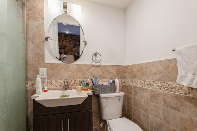 bathroom with vanity, toilet, and tile walls