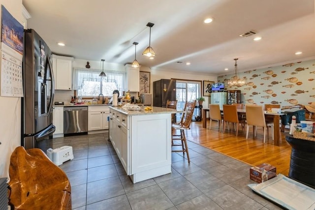 kitchen with appliances with stainless steel finishes, a center island, decorative light fixtures, and a healthy amount of sunlight