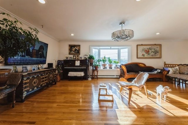 living area with hardwood / wood-style floors, baseboard heating, and crown molding