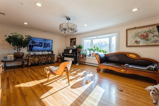 sitting room featuring ornamental molding, baseboard heating, and light hardwood / wood-style flooring