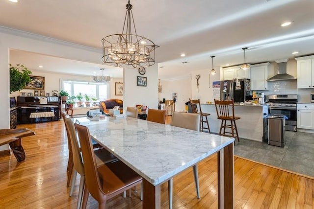 dining space featuring an inviting chandelier, ornamental molding, and light hardwood / wood-style flooring