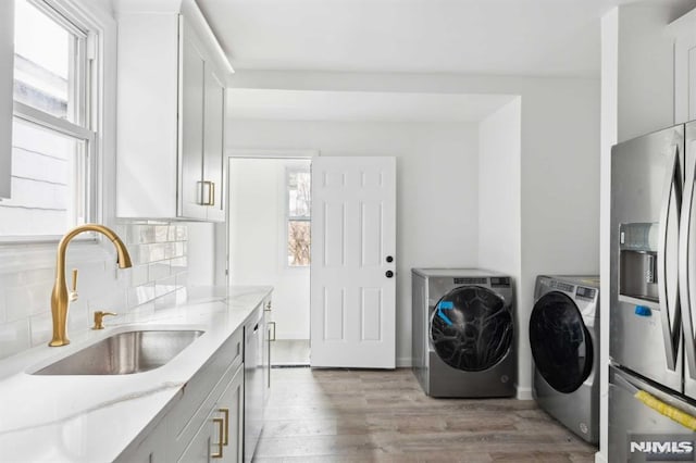 laundry room featuring sink, separate washer and dryer, and light hardwood / wood-style flooring