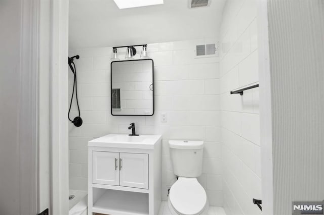 bathroom featuring toilet, a tile shower, and vanity