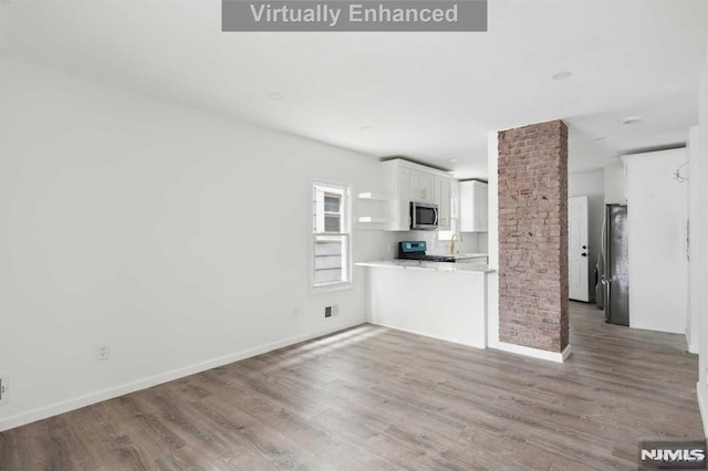 unfurnished living room with sink, ornate columns, and hardwood / wood-style flooring