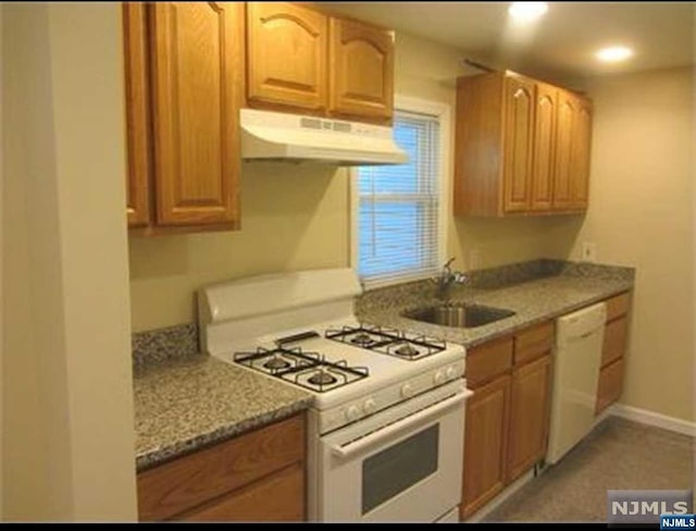 kitchen featuring dark stone countertops, sink, and white appliances