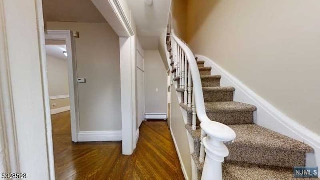 staircase featuring wood-type flooring and baseboard heating