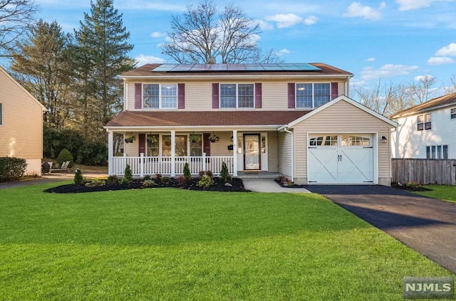 view of front of property with solar panels, a porch, a garage, and a front yard