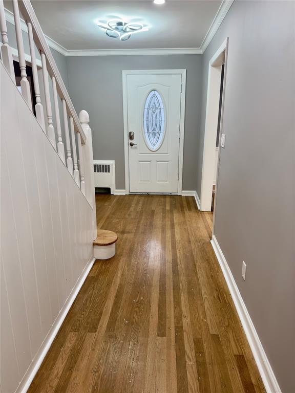 entryway with hardwood / wood-style flooring, radiator, and crown molding