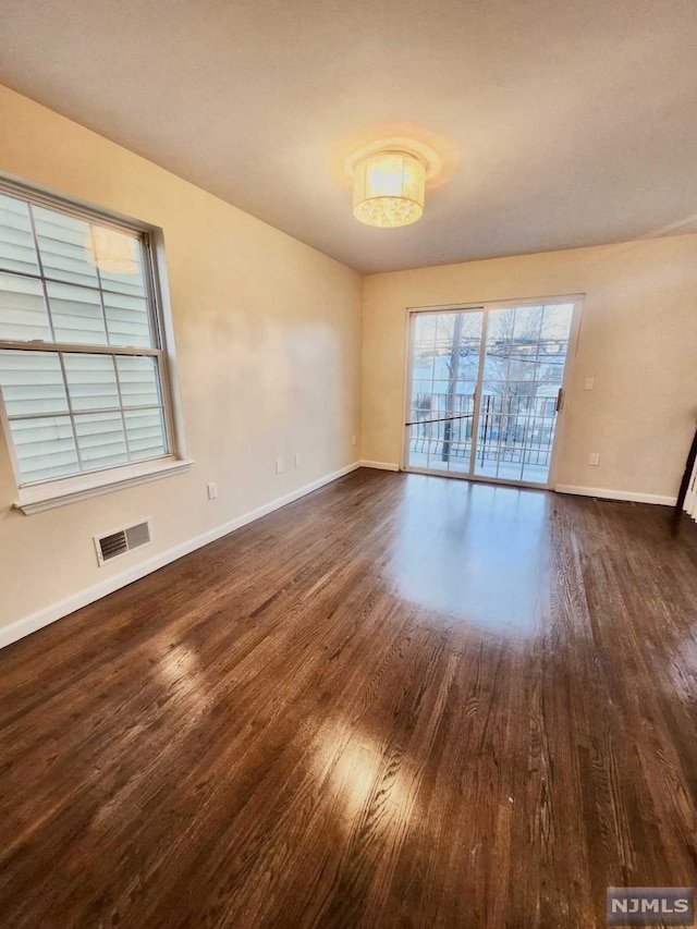 empty room with plenty of natural light and dark hardwood / wood-style floors