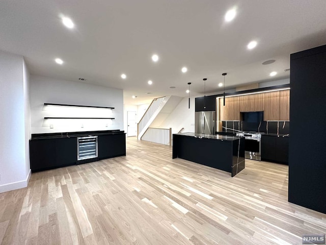 kitchen with a center island, wine cooler, light hardwood / wood-style floors, decorative light fixtures, and appliances with stainless steel finishes