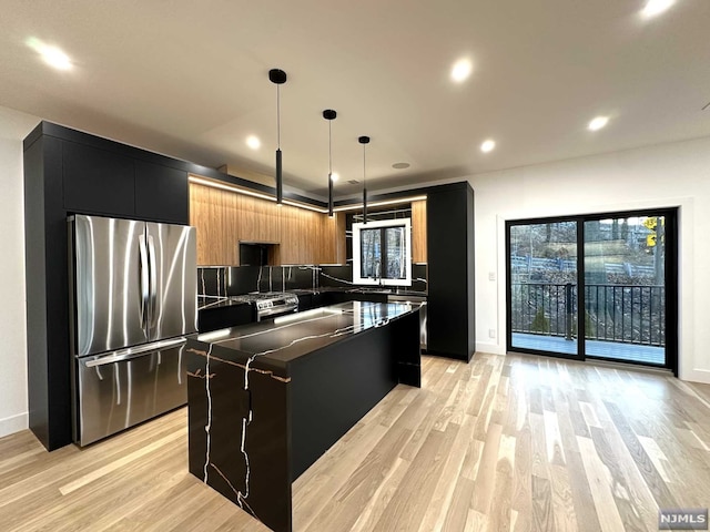 kitchen with a center island, hanging light fixtures, decorative backsplash, a wealth of natural light, and stainless steel refrigerator