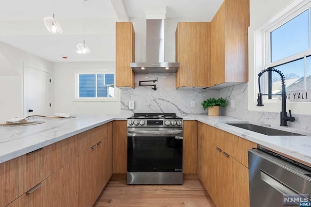 kitchen featuring a wealth of natural light, wall chimney exhaust hood, light hardwood / wood-style floors, and appliances with stainless steel finishes