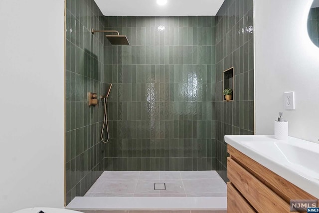 bathroom featuring a tile shower and vanity