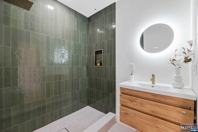 bathroom featuring a tile shower, tile patterned flooring, and vanity