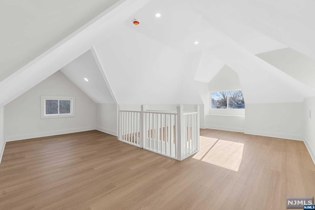 additional living space with light hardwood / wood-style flooring and vaulted ceiling