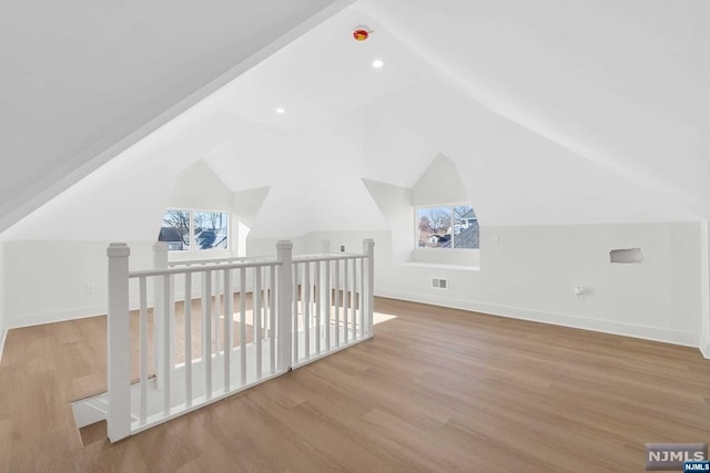 additional living space with light wood-type flooring and vaulted ceiling