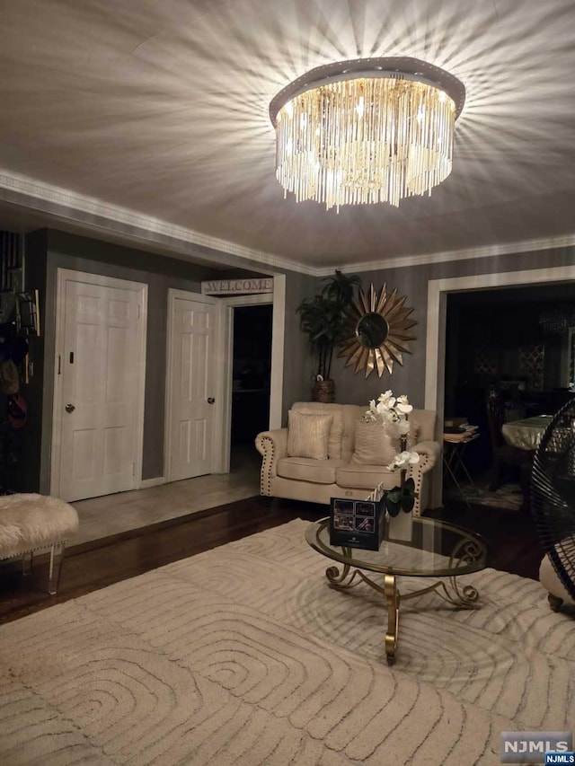 living room featuring wood-type flooring, an inviting chandelier, and ornamental molding