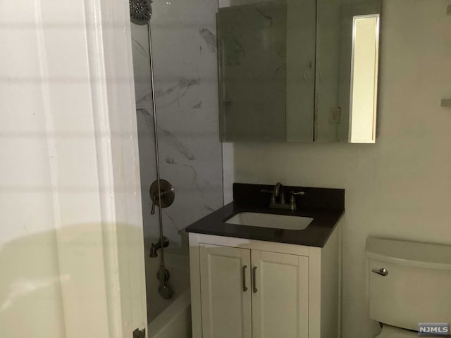 full bathroom with vanity, tiled shower / bath combo, and toilet