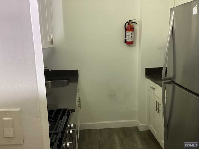 kitchen with white cabinets, stainless steel fridge, dark hardwood / wood-style flooring, and sink