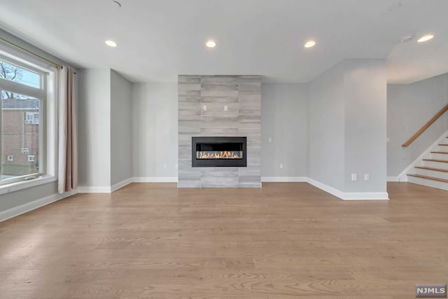 unfurnished living room featuring a tile fireplace and light hardwood / wood-style flooring