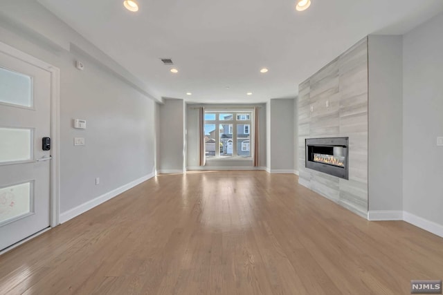 unfurnished living room featuring light wood-type flooring and a fireplace