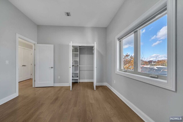 unfurnished bedroom with hardwood / wood-style floors and a closet