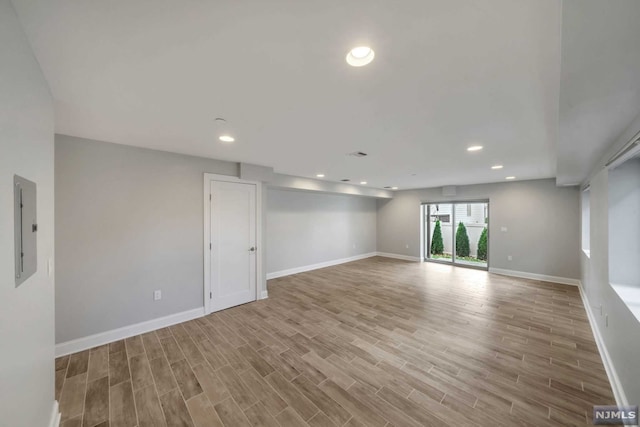 spare room featuring electric panel and light hardwood / wood-style flooring