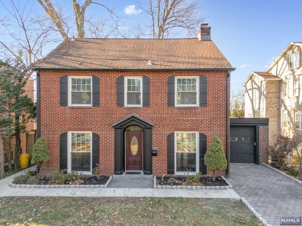 colonial home with a garage and an outbuilding