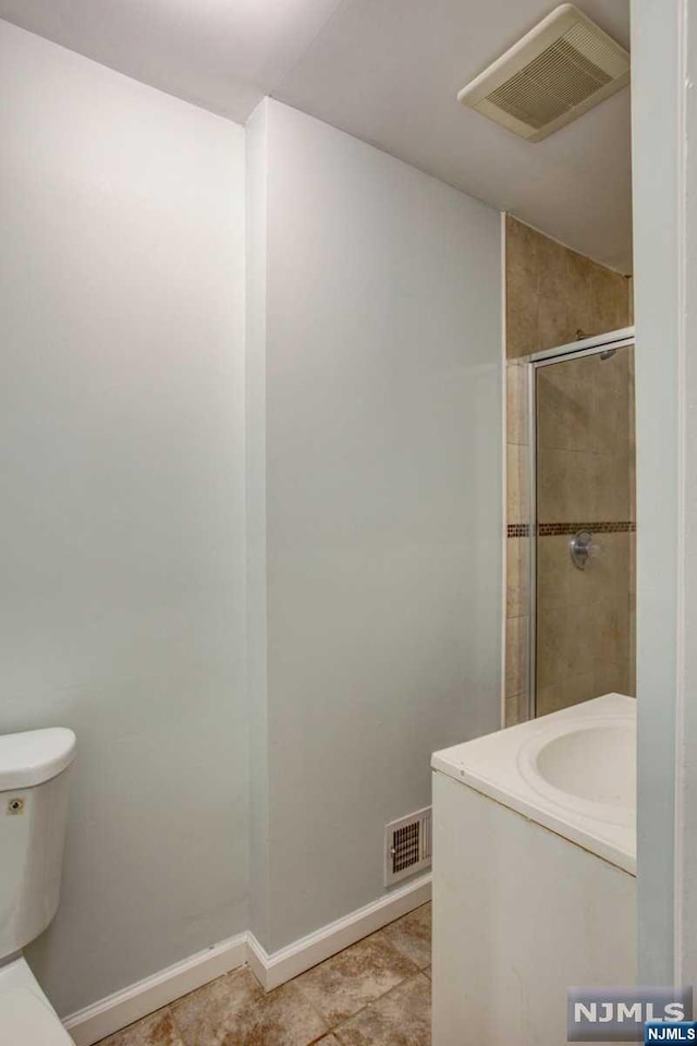 bathroom with tile patterned floors, vanity, an enclosed shower, and toilet