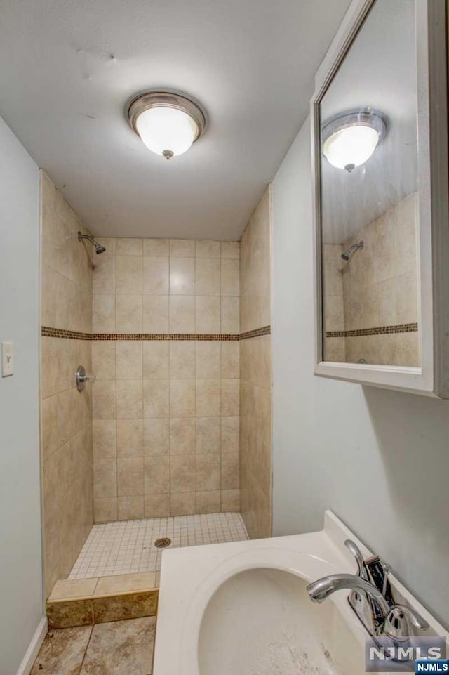 bathroom with tile patterned floors, sink, and tiled shower