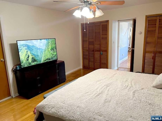 bedroom featuring wood-type flooring, two closets, and ceiling fan