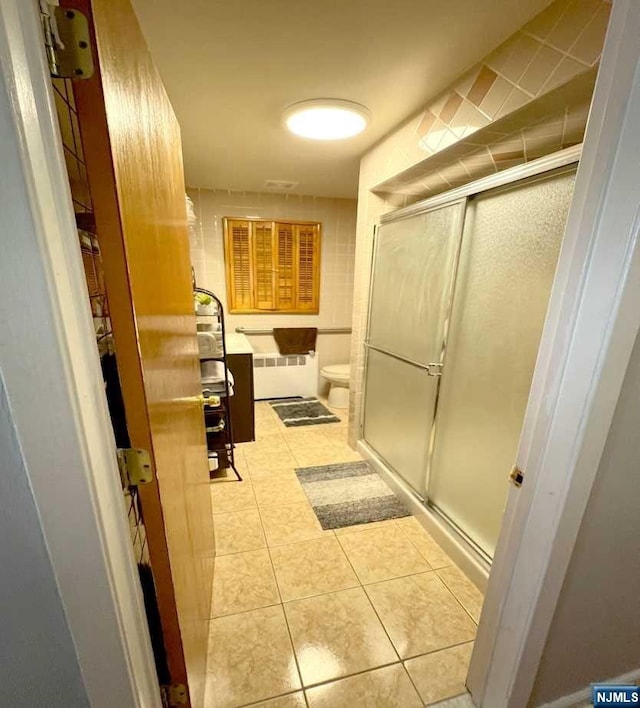 bathroom with radiator heating unit, walk in shower, tile patterned flooring, toilet, and vanity