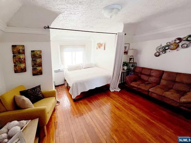 bedroom featuring hardwood / wood-style flooring, a textured ceiling, and vaulted ceiling