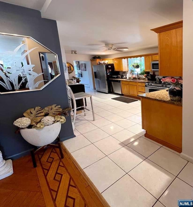 kitchen with light tile patterned floors, stainless steel appliances, ceiling fan, and sink