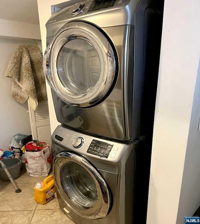 laundry area with stacked washer and dryer and light tile patterned floors