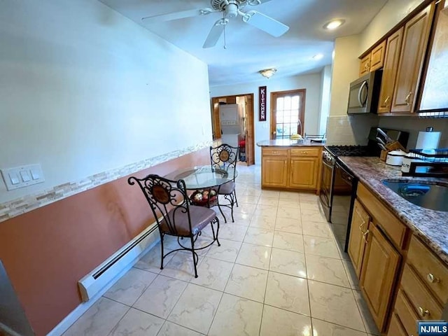 kitchen featuring ceiling fan, sink, baseboard heating, dark stone countertops, and black appliances