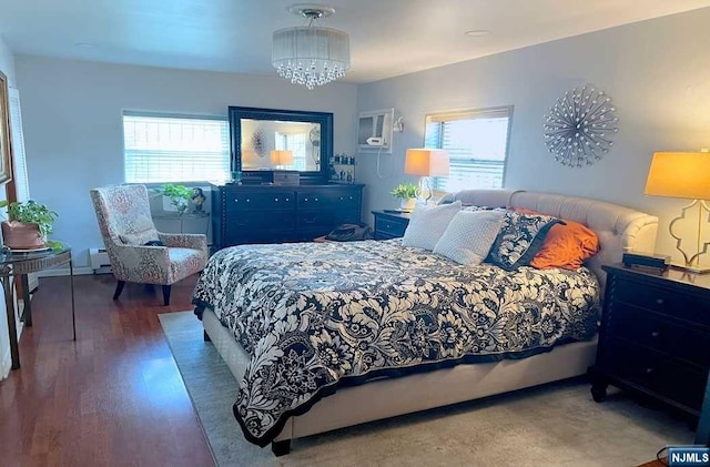 bedroom with an inviting chandelier, dark hardwood / wood-style flooring, baseboard heating, and multiple windows