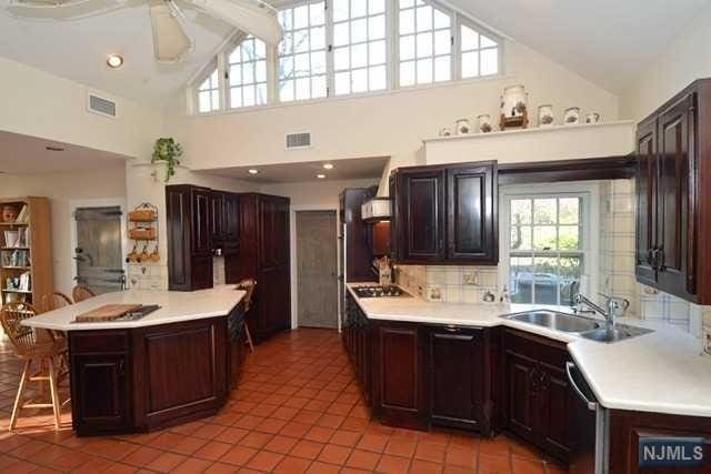 kitchen featuring dark brown cabinets, sink, light tile patterned floors, high vaulted ceiling, and dishwasher