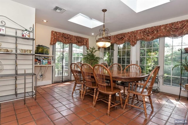 dining space with a skylight and dark tile patterned floors