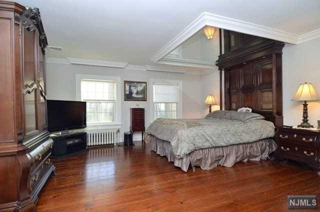 bedroom featuring crown molding, dark wood-type flooring, and radiator