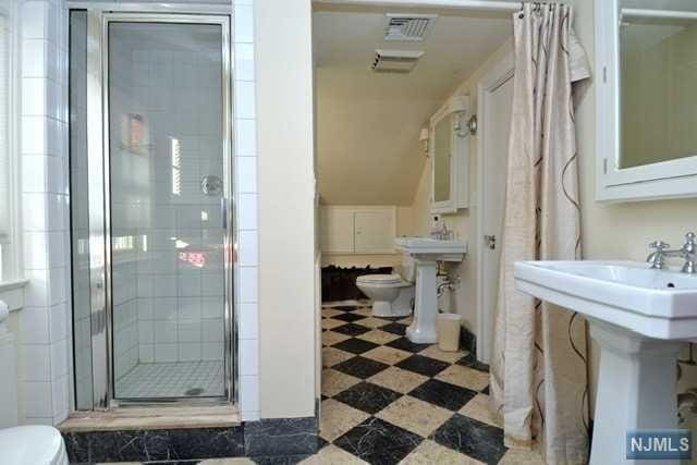 bathroom featuring toilet, an enclosed shower, and sink