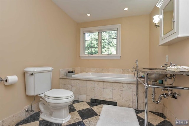 bathroom with a relaxing tiled tub and toilet